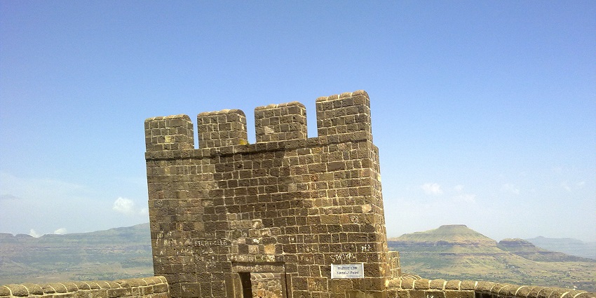 An image of the historical architecture of Shivneri Fort, with scenic hill views below.