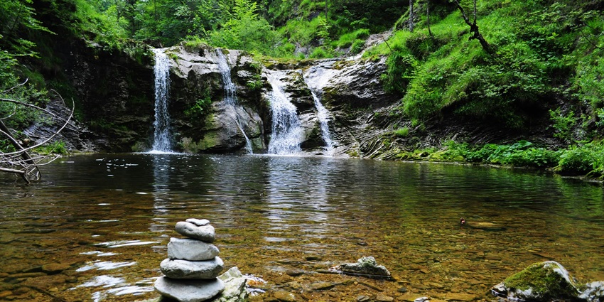 A waterfall surrounded by lush green forest, a famous places near Gandharpale Caves.