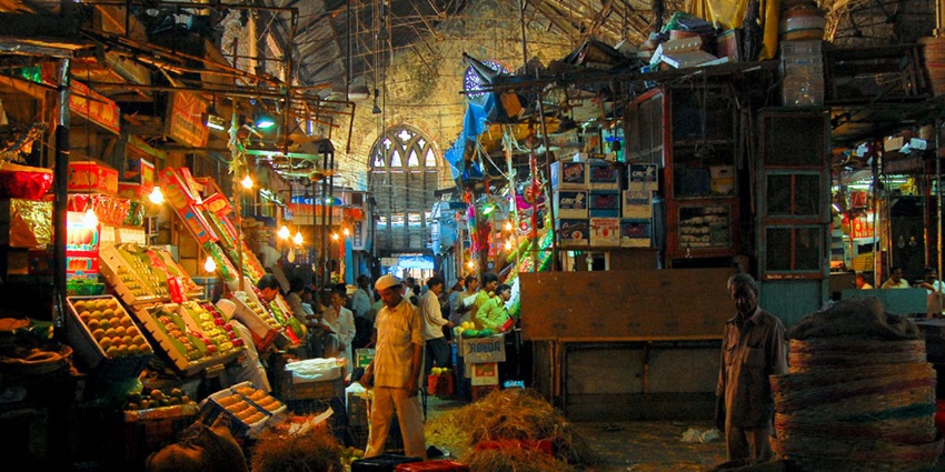 Vibrant fruit stalls at Crawford Market, Mumbai, displaying colorful produce and bustling activity.