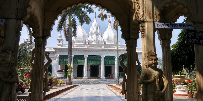 View of the Adniath temple from an archway hall, surrounded by tall palm trees