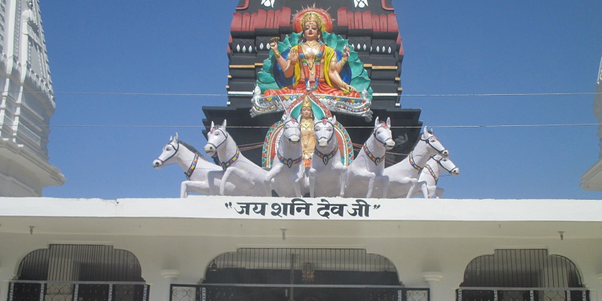 A frontal view of a Shani Dev Temple in Navi Mumbai with a tall statue over its roof