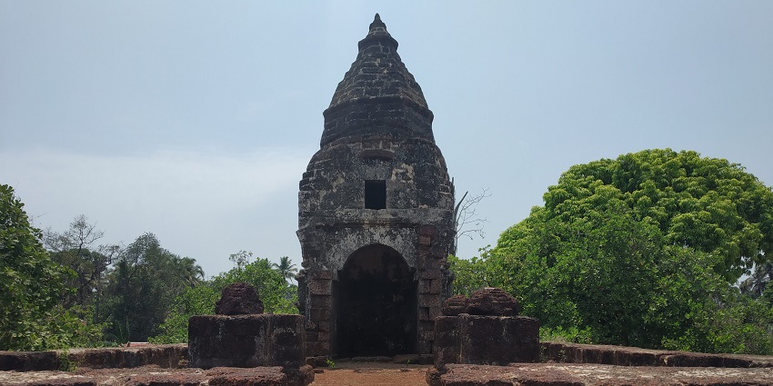 Temple building surrounded by lush shrubs against the clear blue sky