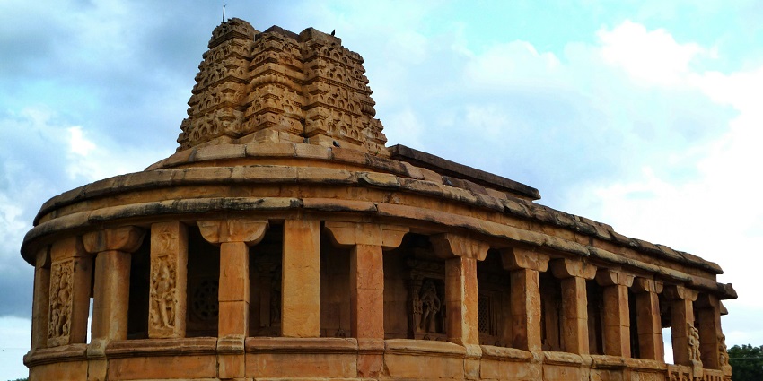 A picture of an ancient temple carved out of rocks, taken on a sunny day