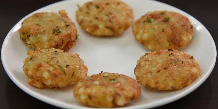 Sabudana Vadas with a fried surface and visible coriander shreds are served on a white plate