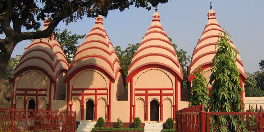 A frontal view of a traditional Shiva temple with a garden area around the walkway