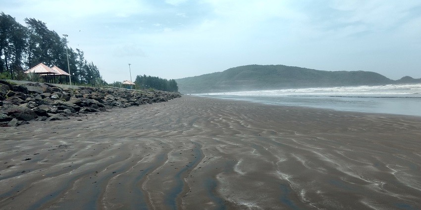 An image of Shrivardhan Beach with crystal clear water, spotless sky and dark brown sand