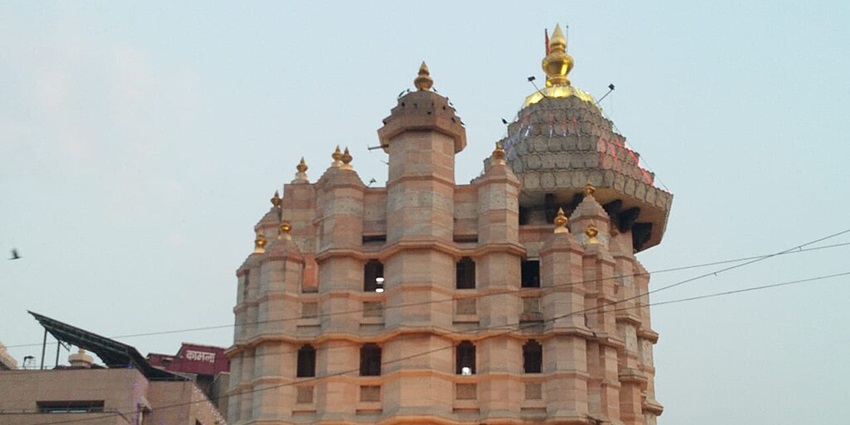 An image view of Siddhivinayak Temple with devotees and lush greenery, showing one of the best places to visit near Gateway of India.
