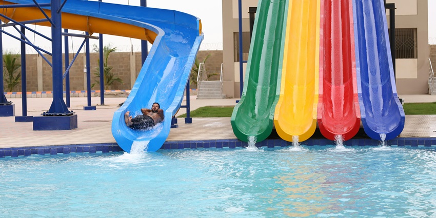 Image of a person sliding into the pool through the colourful waterslides in an adventure park
