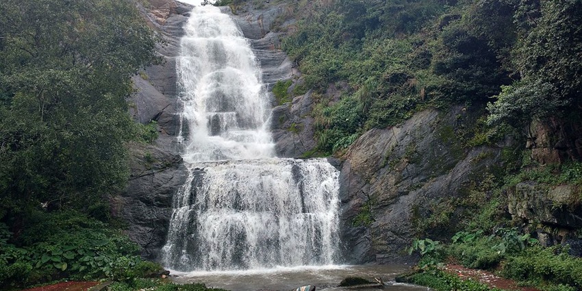Silver Cascade waterfall in Kodaikanal with prolific greenery and flowing water over rocky terrain