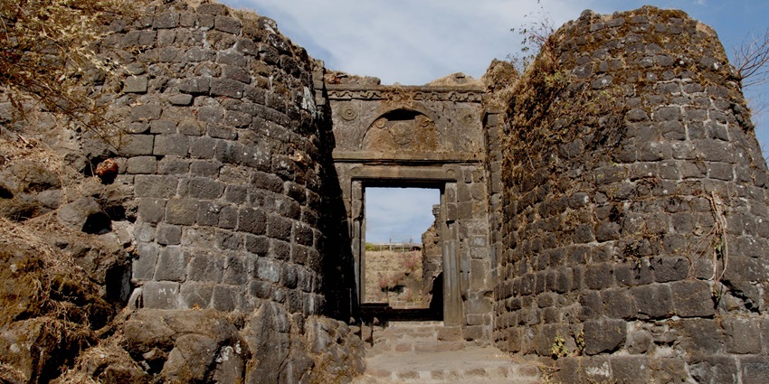 Historic Sinhagad Fort perched on a hilltop with panoramic views and cloudy skies.