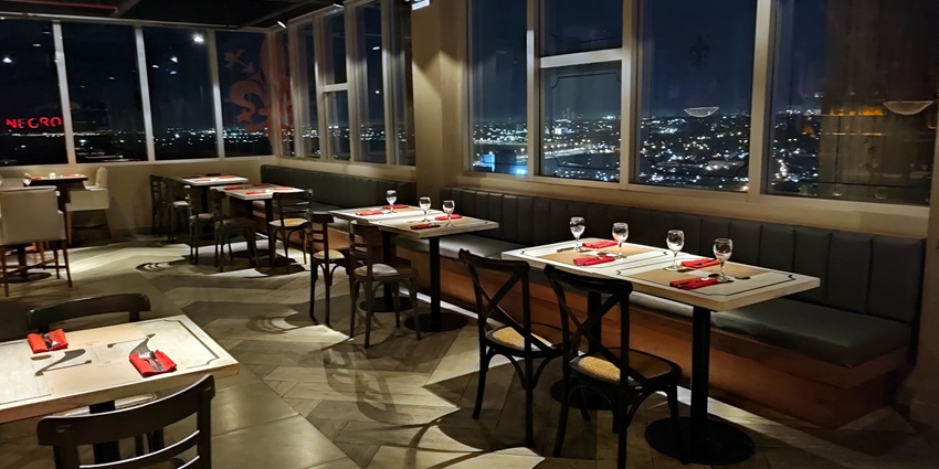 Stylish rooftop bar with cosy seating, ambient lighting, and an evening city backdrop.