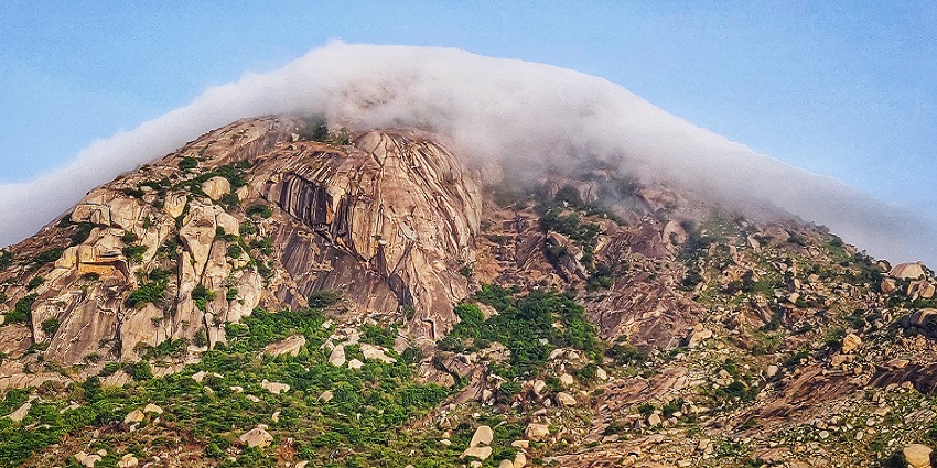 A stunning view of clouds covering the peak of Skandagiri.