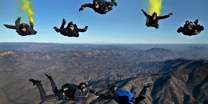 A picture of skydivers enjoying the breathtaking view during free fall above scenic landscapes.