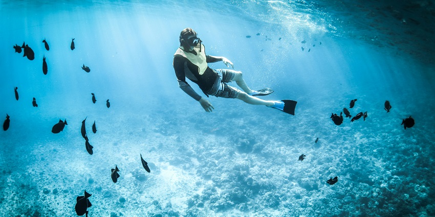 An image showing a person snorkelling in clear blue water surrounded by Gili Islands
