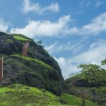 A scenic view of Sondai Fort with green hills and cloudy skies in Maharashtra, India.