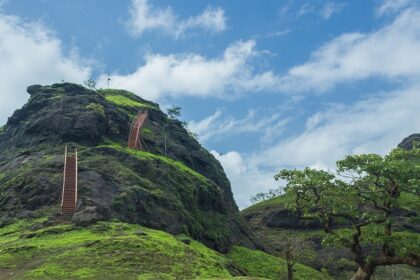 A scenic view of Sondai Fort with green hills and cloudy skies in Maharashtra, India.