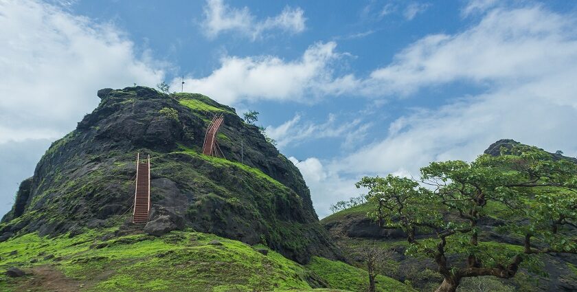 A scenic view of Sondai Fort with green hills and cloudy skies in Maharashtra, India.