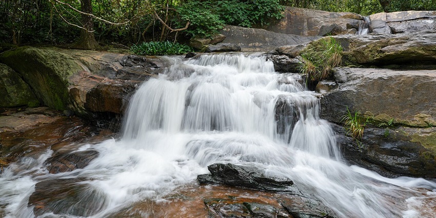 A serene waterfall in Kalasa, cascading down a rocky hill with lush surroundings