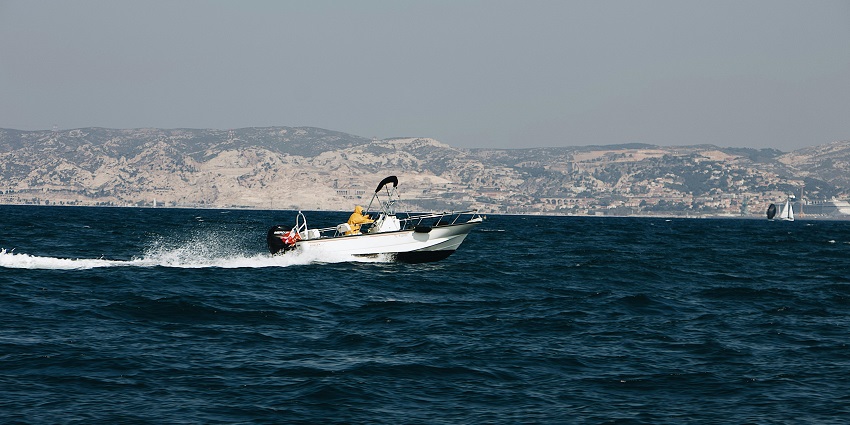 A picture of a speedboat going along the Tarkarli coastline, making waves.