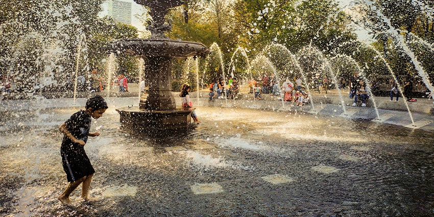 Children joyfully playing in a water fountain, splashing water and enjoying a sunny day