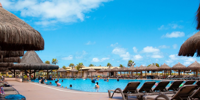 Image of a swimming pool people enjoying during day time - clear water and sky
