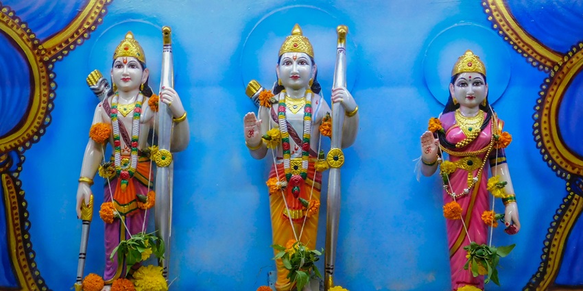 Statues of Ram ji, Laxman ji and Mata Sita adorned in garlands in a light blue background