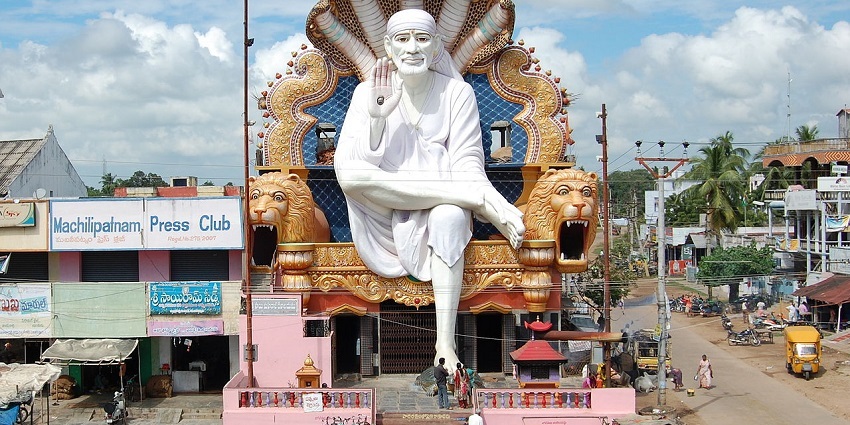 A picture of a tall statue of Sai Baba at a temple in Faridabad