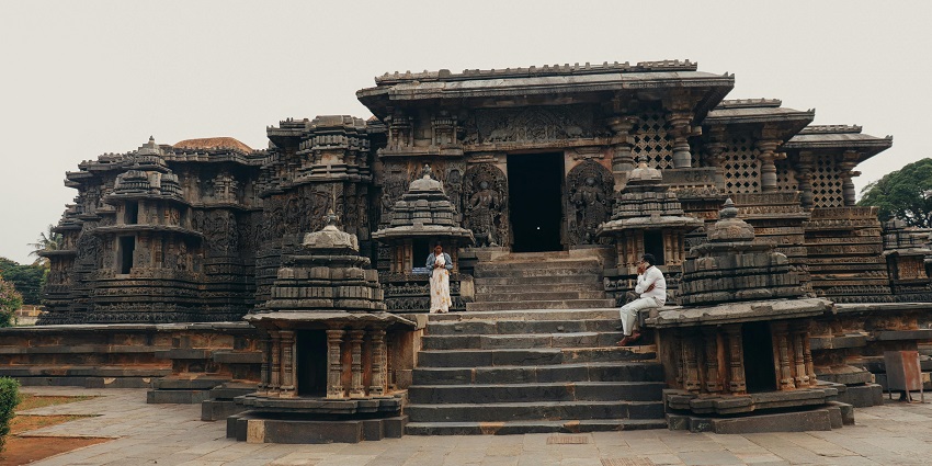 People gathered in front of a majestic temple in Madurai with ornate carvings and towering spires.