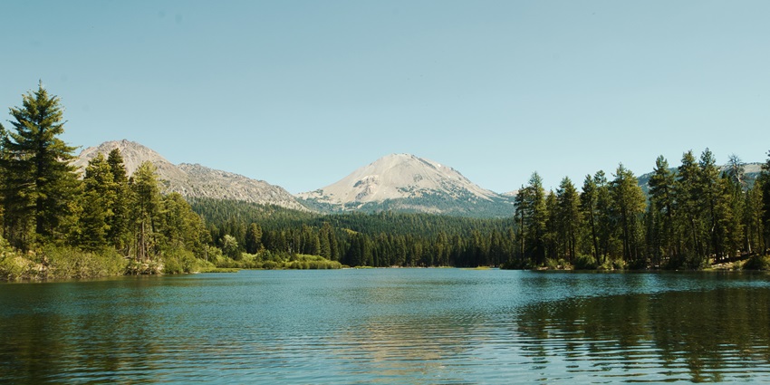 Calm waters of Srinivasa Sagara Kere surrounded by greenery and open skies.
