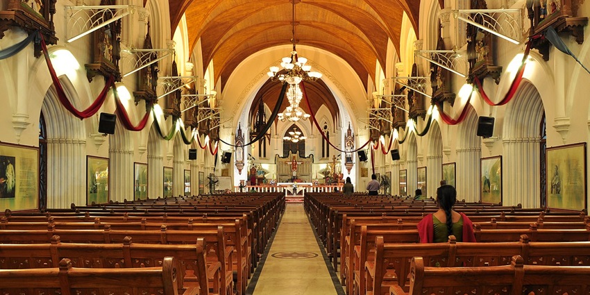 Interior of a grand church with arched ceilings, stained glass windows, and wooden pews.