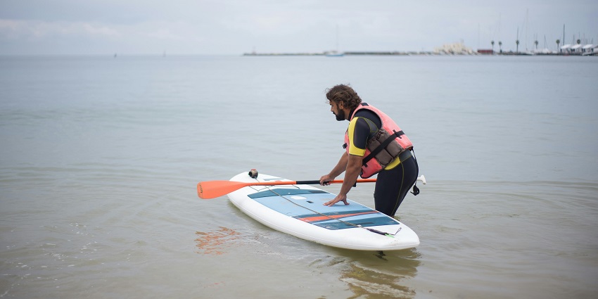 An image of a person paddleboarding on the calm waters of Mulshi Lake, with hills.
