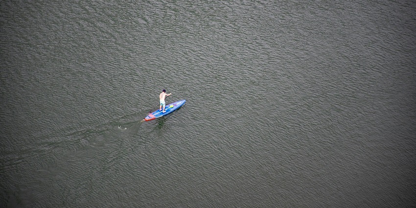 An image of a person paddle boarding on Lavasa's lake, one of the best Lavasa water sports.