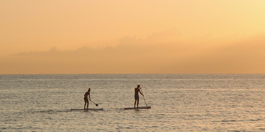 A picture of a man and woman paddleboarding, one of the best Tarkarli water sports.