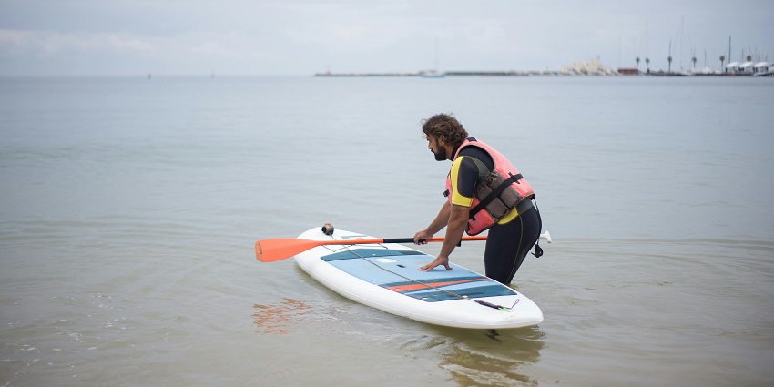 An image of a person standing up paddleboarding on the calm waters of Mandwa Beach.
