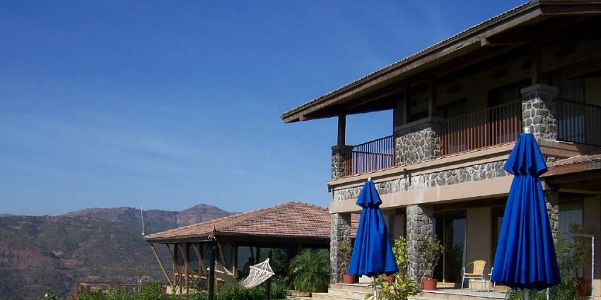 View of Ekaant Retreat with forest-class amenities and lush mountains in the backdrop.