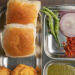 Glass jars filled with different items and man cutting tomato for bhelpuri preparation