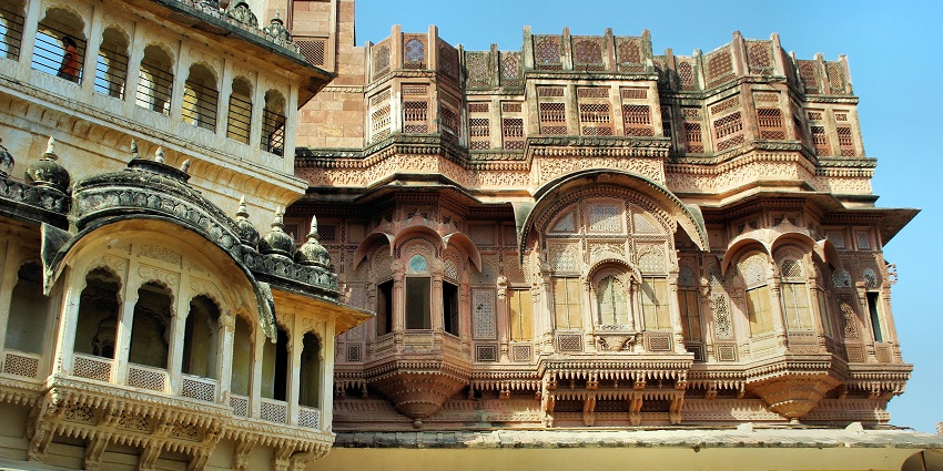 A palace that has numerous windows with intricate carving and is vibrantly coloured