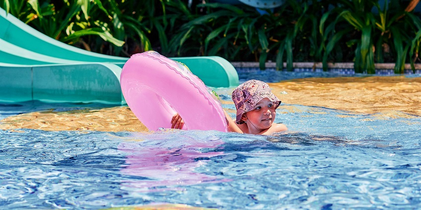 Boy swimming with a floater at a water park on a bright sunny day and blue sky.