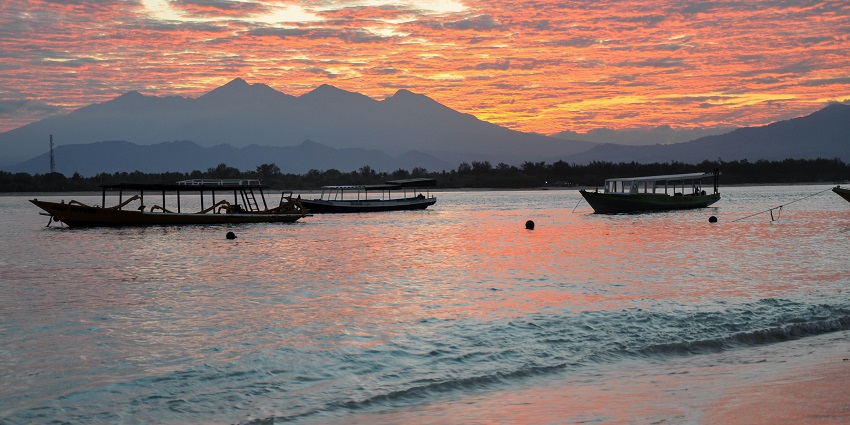 Picture of the sunset on Gili Trawangan island with a mountain view and boats around.