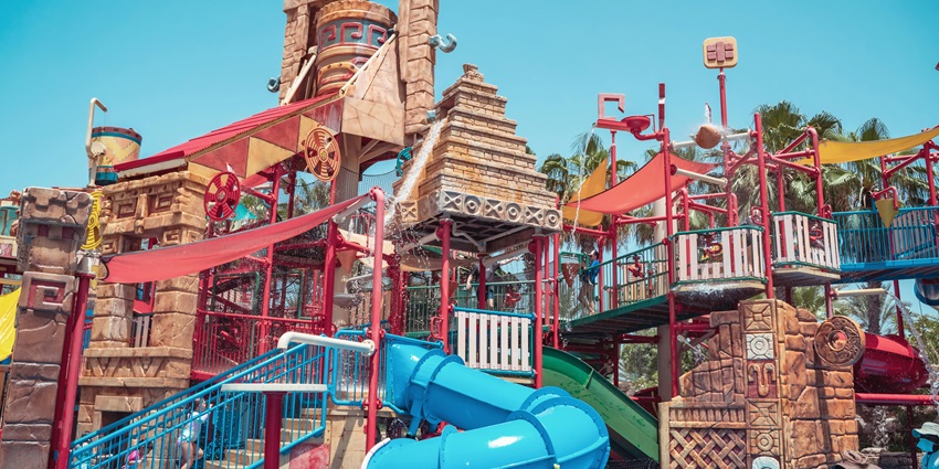 An image of colourful slides and a pool, showcasing children enjoying the summer day