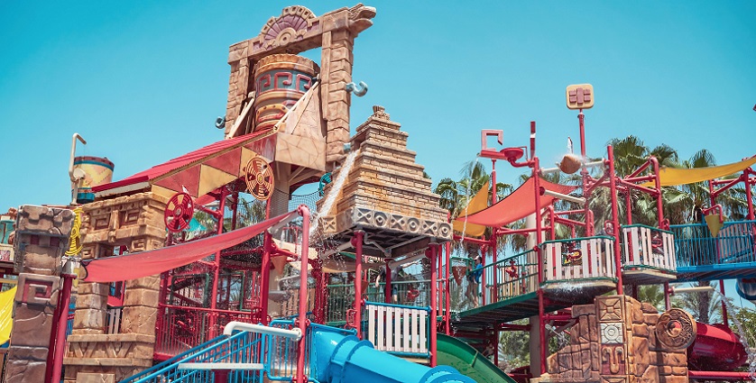 A view of Matheran Waterpark with colourful slides and pools and children running.