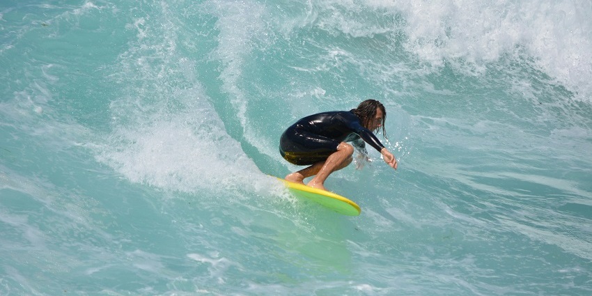 A beautiful view of a man surfing on high sea waves on the Kuta beach in Indonesia.