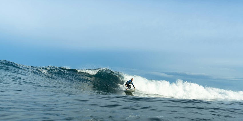 A thrilling exciting image of surfers surfing at Blue Point Beach during the daytime.