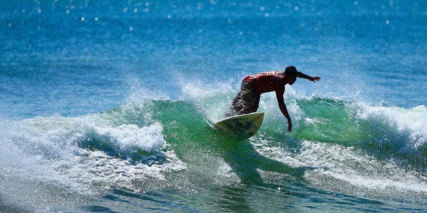 People surfing at the Kuta beach, while others are enjoying the shore, Indonesia.