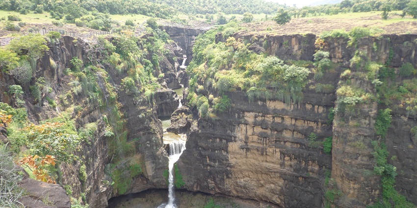 Cascading water plunges dramatically amidst lush green surroundings