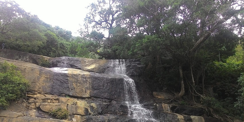 Tourists enjoying the cascading waters at the Suruli Waterfalls in Tamil Nadu