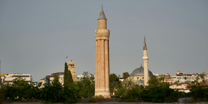 Ancient beige stone pillar standing tall near green trees in an open natural setting