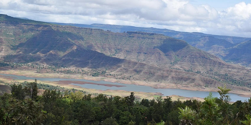 A panoramic view of the vast natural landscape in Satara, with a river flowing in front of hills