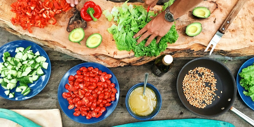 Image of people cooking with colourful vegetables on the table - Cooking Class in Ubud