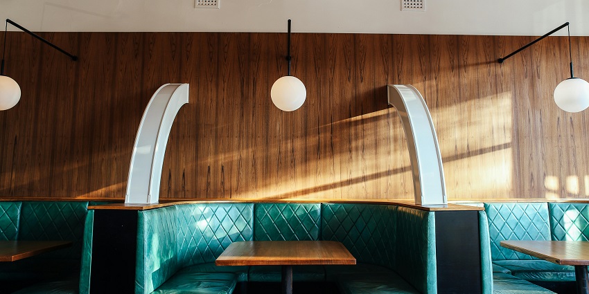 Interior of a modern restaurant with leather seats, wooden tables, and warm lighting.